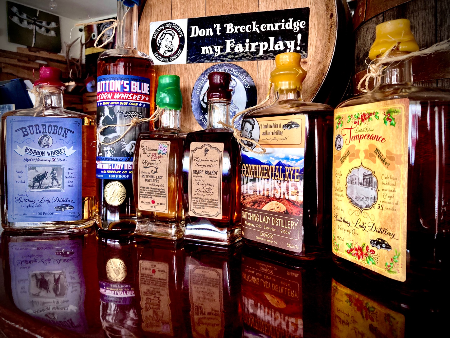 Lineup of Snitching Lady Distillery bottles — Burrobon, Button's Blue Corn Whiskey, Böhena Apple Brandy, Appalachian Temptation Grape Brandy, Continental Rye and Temperance Wheat Whiskey